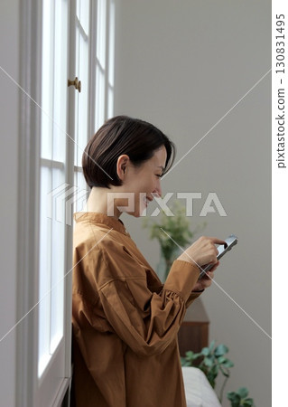 A woman who manipulates a smartphone at the window side 130831495
