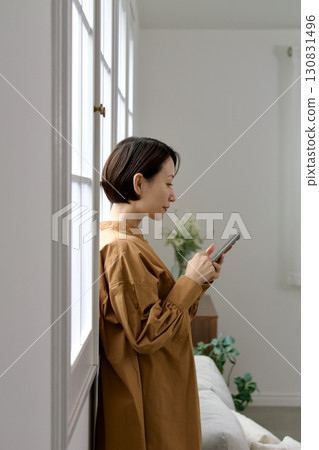 A woman who manipulates a smartphone at the window side 130831496