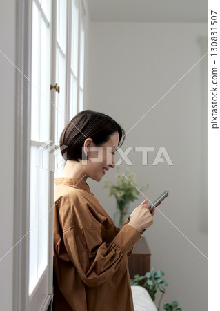 A woman who manipulates a smartphone at the window side 130831507