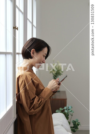 A woman who manipulates a smartphone at the window side 130831509