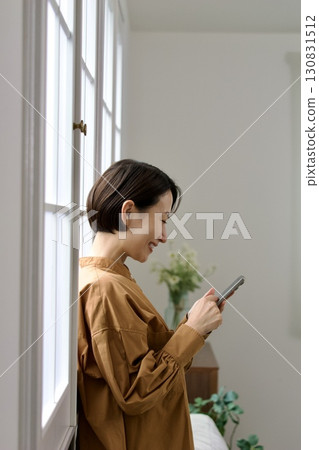 A woman who manipulates a smartphone at the window side 130831512