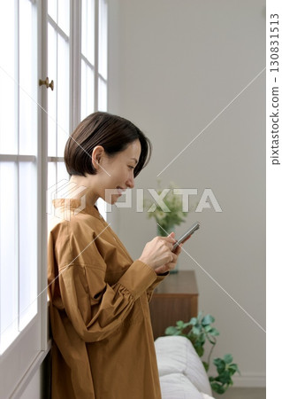 A woman who manipulates a smartphone at the window side 130831513