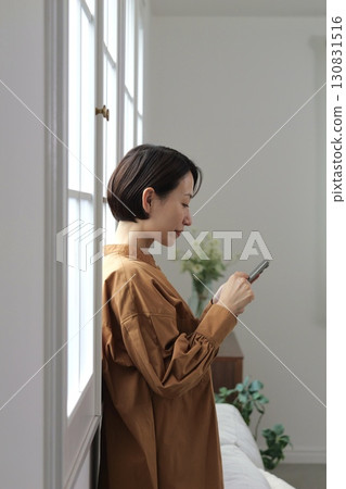 A woman who manipulates a smartphone at the window side 130831516