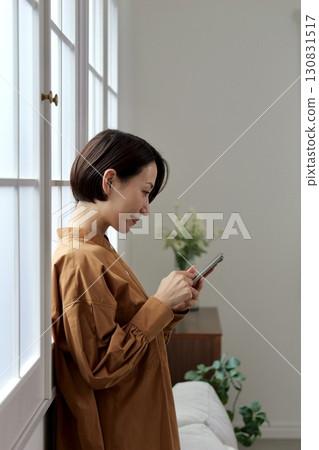 A woman who manipulates a smartphone at the window side 130831517