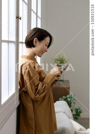A woman who manipulates a smartphone at the window side 130831518