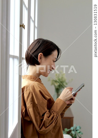 A woman who manipulates a smartphone at the window side 130831519
