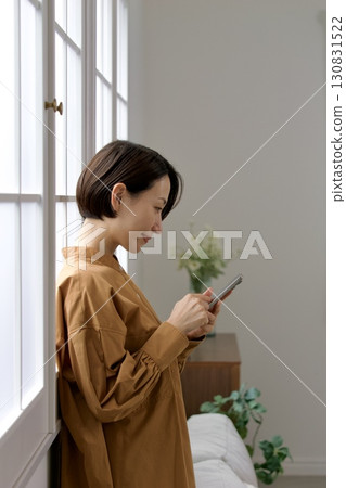一個在窗邊操縱智能手機的女人 130831522