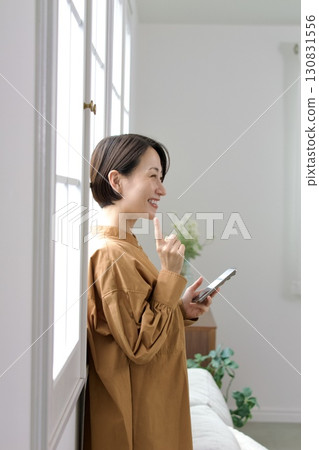 A woman who manipulates a smartphone at the window side 130831556
