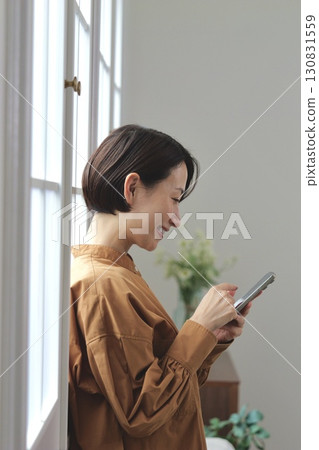 A woman who manipulates a smartphone at the window side 130831559