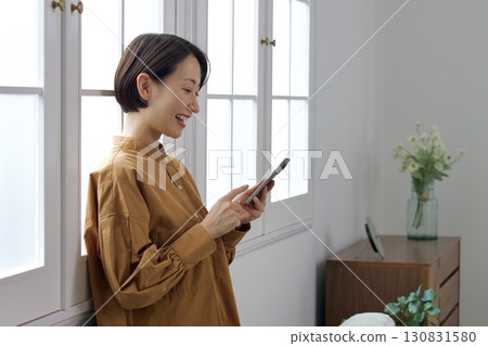 A woman who manipulates a smartphone at the window side 130831580