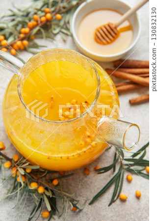 Glass teapot with sea buckthorn tea, honey and cinnamon sticks on table Glass teapot with sea buckthorn tea, honey and cinnamon sticks on table 130832130