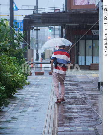 A middle-aged man walking alone in the street in front of Takayama Station on a rainy day A middle-aged man walking alone in the street in front of Takayama Station on a rainy day 130832865