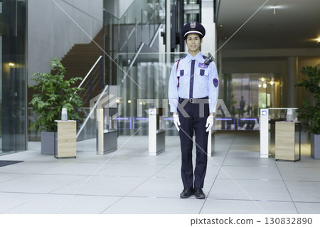 A young security guard standing in the entrance lobby of an office building. Photo courtesy of Sky Perfect Tokyo Media Center. 130832890