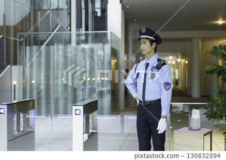 A young security guard standing at the entrance/exit gate of an office building. Photo courtesy of Sky Perfect Tokyo Media Center 130832894