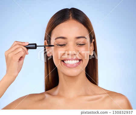 Woman, beauty and mascara makeup for eyes with cosmetics on face in studio. Female model person smile on a blue background for self care, facial glow and eyelash extension or luxury growth product 130832937