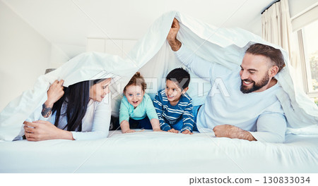 Family, blanket and fun by children and parents in bed, happy and smile while playing and bonding in their home. Bedroom, fort and kids with mother and father, waking up and enjoying weekend indoors Family, blanket and fun by children and parents in bed, happy and smile while playing and bonding in their home. Bedroom, fort and kids with mother and father, waking up and enjoying weekend indoors 130833034