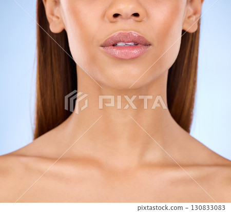 Lips, shine and beauty with face and woman in closeup for cosmetic care and lipstick on blue background. Skin glow, dermatology and skincare, female with lip filler and facial with makeup in studio 130833083
