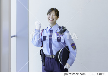 Portrait of a young female security guard standing by a window, pumping her fist in excitement. Photo courtesy of Tokyo Electronics College, Denpa Gakuen Corporation 130833098