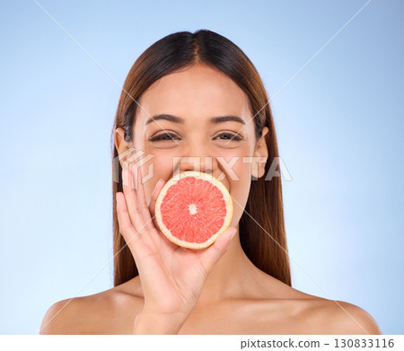 Grapefruit, woman and beauty face portrait for skincare dermatology and vitamin c. Female model on a blue background for self care, facial glow and healthy fruit for natural and clean skin in studio Grapefruit, woman and beauty face portrait for skincare dermatology and vitamin c. Female model on a blue background for self care, facial glow and healthy fruit for natural and clean skin in studio 130833116