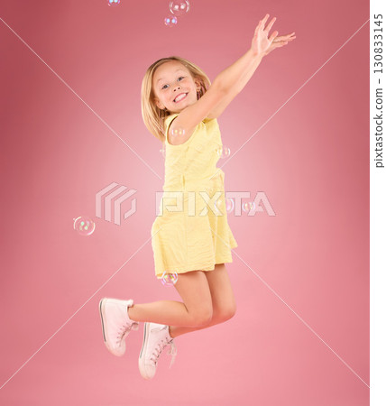 Child, jump and bubbles for a smile portrait in studio with a pink background for fun. Female kid model jumping with happiness, play and cheerful face isolated on gradient color and space 130833145