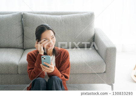 坐沙發和操作智能手機的一個少婦 130833293