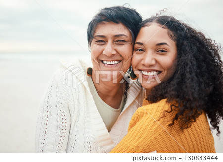 Happy, hug and portrait of a mother and daughter at the beach for travel, bonding and vacation. Family, smile and elderly mom with an adult woman at the ocean to relax together for happiness 130833444