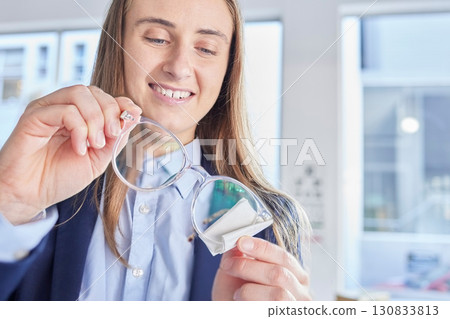 Glasses, vision and an optometrist woman cleaning lenses in a store to sell a product for fashion. Hands, eyewear and optometry with a female optician wiping a pair of frame eyeglasses for eyesight 130833813