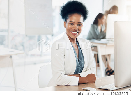 Leadership, happy and portrait of a businesswoman in the office with a computer working on a project. Happiness, smile and African female corporate manager sitting at her desk with a pc in workplace. 130833825
