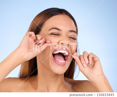 Dental floss, tooth cleaning and woman smile with teeth hygiene, healthcare and wellness treatment. Isolated, blue background and studio with a female feeling beauty from a clean mouth with self care 130833845