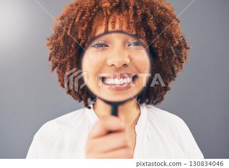 Magnifying glass, focus and smile with portrait of black woman for analysis, exploration and close up. Detective, search and spy with girl and magnifier for investigation, zoom or discovery in studio 130834046