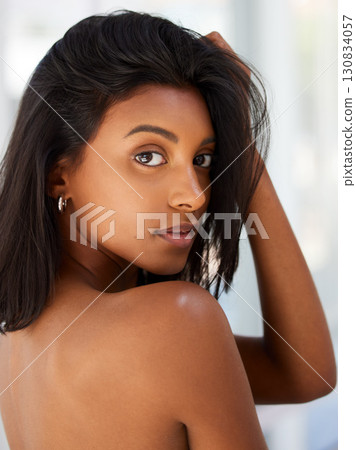 Portrait, beauty and confidence with an indian woman in her home, feeling beautiful or sensual. Face, hair and relax with an attractive young female in her apartment looking confident or feminine 130834057