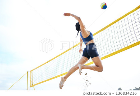 Volleyball, sports and woman jump at beach to hit ball in competition, game or match. Training, exercise and female athlete jumping for spike in tournament for workout, fitness and health at seashore 130834216