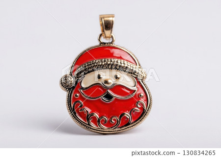 Vintage Santa Claus pendant, with a red and white enamel colors, a little face with a long beard, in a brass setting. White table blank background. Cute Christmas decoration. Keychain, antique brooch 130834265
