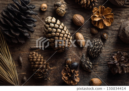 Pine cones on a wooden table, close-up view, blurred background, bokeh effect, macro. Christmas and winter design. Dry, coniferous tree cones. DIY. Autumn, fall mood. Earth tones, natural colors 130834414