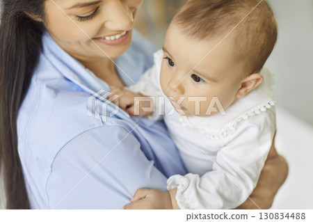 Intimate close-up of a mother smiling and cuddling her baby at home, cozy moment Intimate close-up of a mother smiling and cuddling her baby at home, cozy moment 130834488