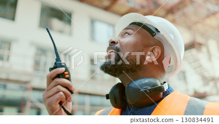 Building, radio and a black man construction worker on a site for project management or development. Communication, safety and an engineer talking on a walkie talkie for industrial architecture Building, radio and a black man construction worker on a site for project management or development. Communication, safety and an engineer talking on a walkie talkie for industrial architecture 130834491