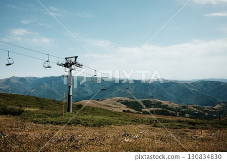 Empty chairlift rising above the green slopes of Stara Planina under a bright summer sky, with panoramic mountain views in the distance. Serbia country 130834830