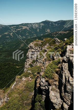 Rocky cliffs and green slopes of Stara Planina with mountain ridges in the distance. Babin Zub mount in summer season. Serbia country Rocky cliffs and green slopes of Stara Planina with mountain ridges in the distance. Babin Zub mount in summer season. Serbia country 130835009