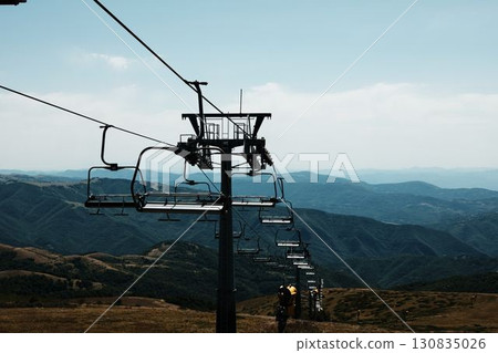 Ski lift chairs on Stara Planina mountain with panoramic view of green hills and valleys. Serbia country in summer season Ski lift chairs on Stara Planina mountain with panoramic view of green hills and valleys. Serbia country in summer season 130835026