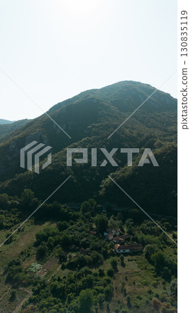 Drone view of Jerma Canyon in Serbia with forested hills and scattered houses. Scenic Balkan mountain landscape under clear blue sky 130835119