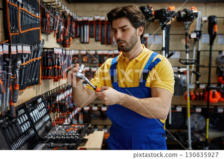 Worker is diligently working on a wrench inside a store Worker is diligently working on a wrench inside a store 130835927