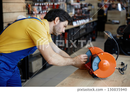 Young worker diligently working on a grinder Young worker diligently working on a grinder 130835940