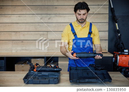 Worker holds a drill securely in a black case 130835950