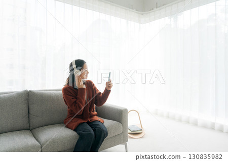 Woman sitting on sofa and listening to music 130835982
