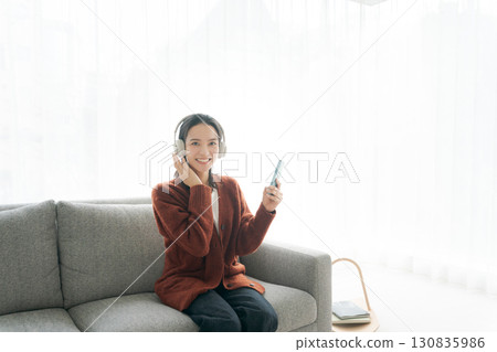 Woman sitting on sofa and listening to music 130835986