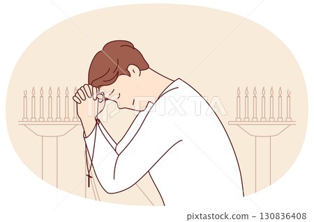 Man prays while standing in church near candlesticks, holds christian crucifix and closes eyes Man prays while standing in church near candlesticks, holds christian crucifix and closes eyes 130836408