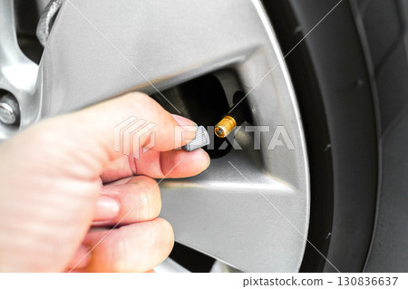 Hand opening tire valve cap on car wheel rim, vehicle air valve for checking tire pressure Hand opening tire valve cap on car wheel rim, vehicle air valve for checking tire pressure 130836637