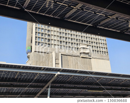 Underside view of a large solar panel installation in Car Park with Under Construction Building. Underside view of a large solar panel installation in Car Park with Under Construction Building. 130836688