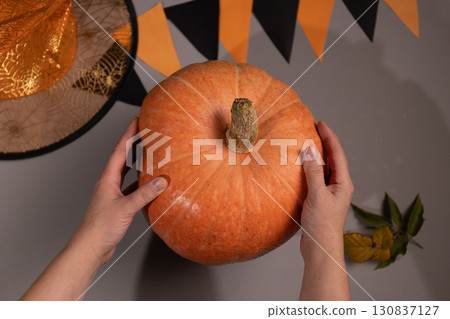 Person Holds Large Pumpkin Before Halloween Decoration Person Holds Large Pumpkin Before Halloween Decoration 130837127