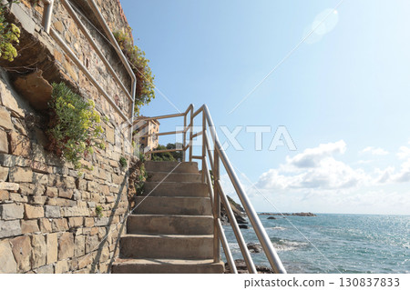 Stone path with iron railings leading to sea on sunny summer day. Nature and buildings. 130837833